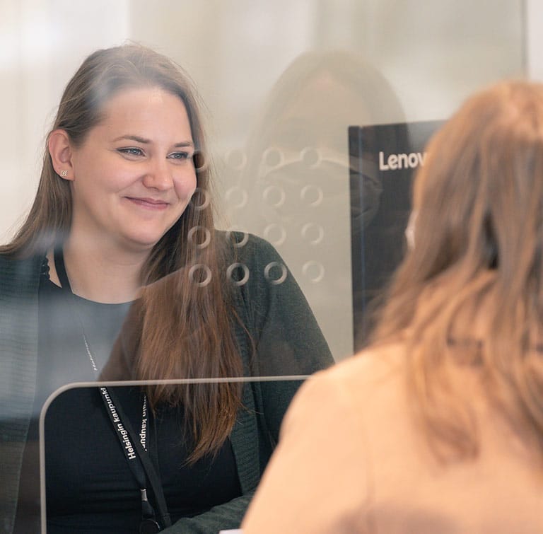 Hymyilevä asiakaspalvelija asiakkaan kanssa.